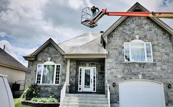 Worker installing hail protection on stone house roof with lift