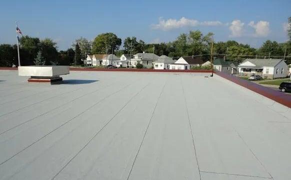 White commercial roof with hail protection coating under clear sky, safeguarding property investments